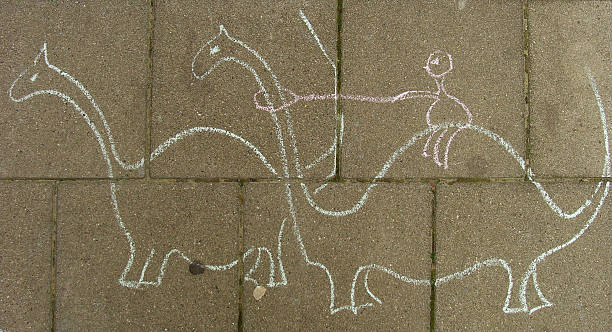 istock chalk dinosaurs hand drawn by kids with chalk on sidewalk 502706851