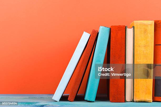 Row Of Colorful Hardback Books Open Book On Red Background Stock Photo - Download Image Now