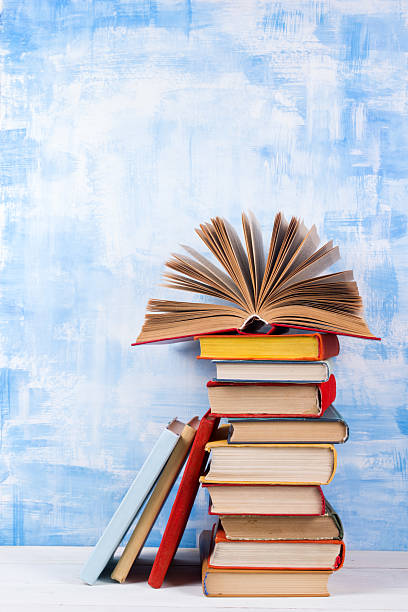 istock Stack of colorful hardback books, open book on blue background 502725128