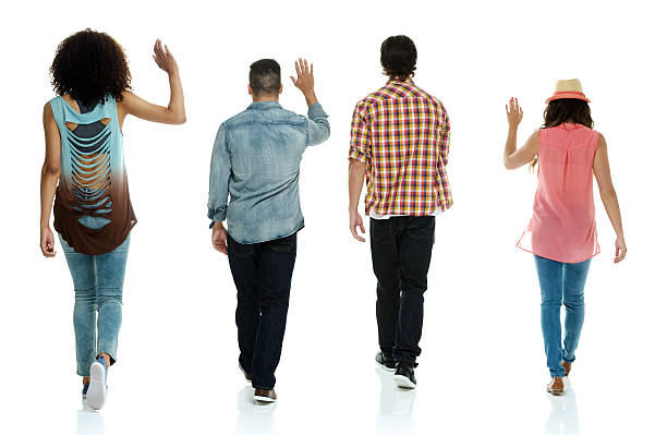 istock Rear view of four people walking & waving hand 502725371