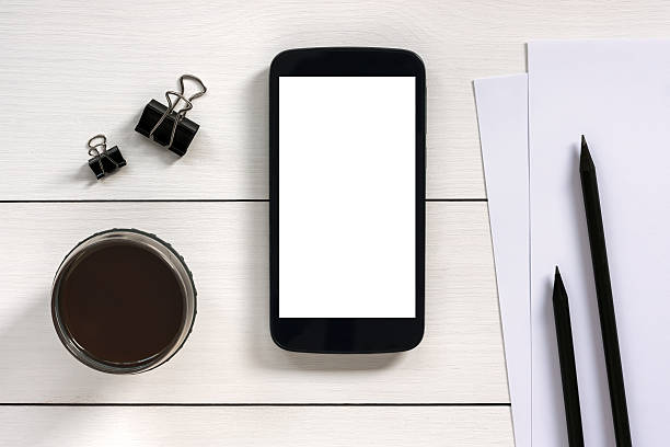 istock Smartphone with white blank empty screen on wooden office desk 502733560