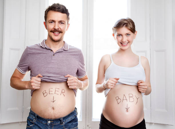 Couple showing their bellies Couple showing their bellies funny pregnancy announcements stock pictures, royalty-free photos & images