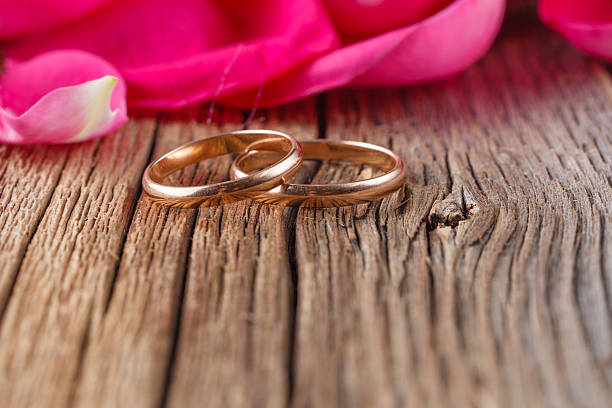 istock Golden rings and rose petals on rustic wood 502739734