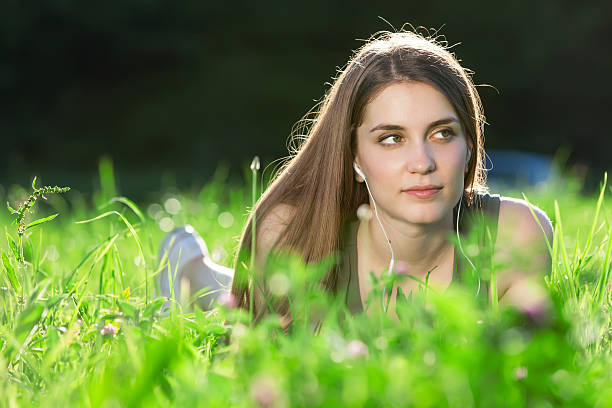 Beautiful young woman sitting on the grass in park stock photo