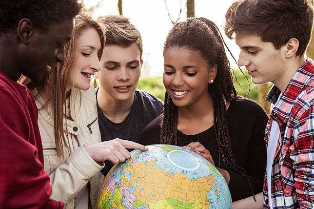 grupo de adolescentes sostiene un globo de tierra - adolescence teenager globe map fotografías e imágenes de stock