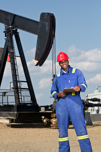 A royalty free image from the oil and gas industry of an oil worker in front of a pumpujack.
