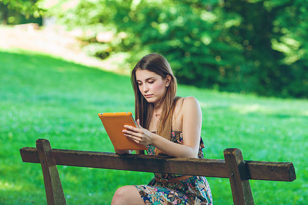 Beautiful young woman sitting on the bench in park stock photo