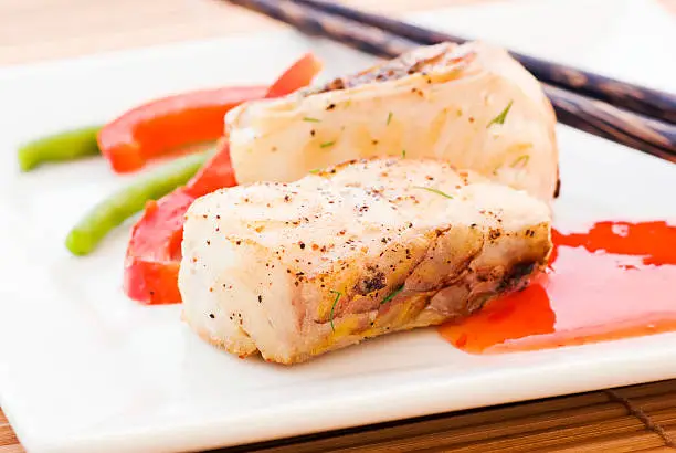 Parrotfish with vegetable and hot chili souce as closup on a white plate