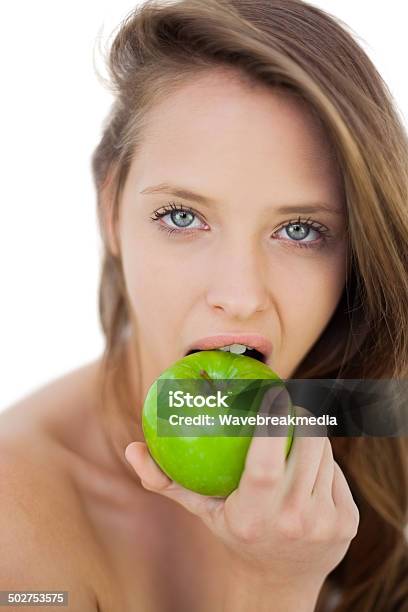 Unsmiling Brunette Model Eating An Apple Stock Photo - Download Image Now - Adult, Adults Only, Apple - Fruit