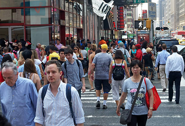 New York, NY, USA - July 2, 2014: A diverse crowd of people cross the street near Times Square in midtown Manhattan.