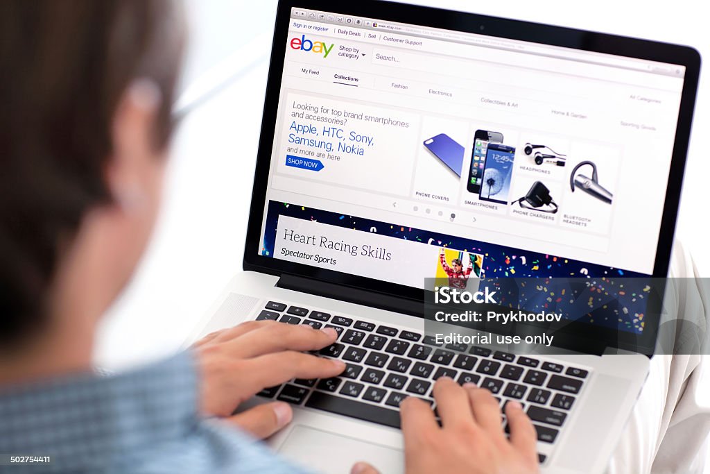 man sitting the MacBook retina with site PayPal on screen Simferopol, Russia - July 9, 2014: eBay the American company that provides services in the areas of online auctions, online shopping, instant payments. eBay Stock Photo