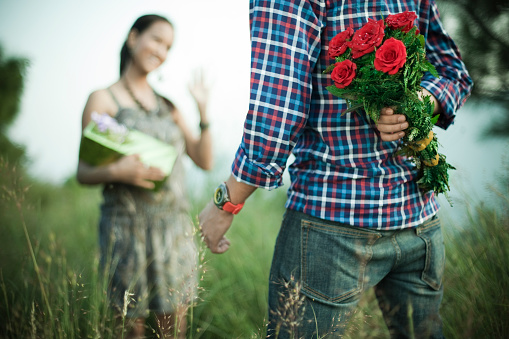 Young man hiding bunch of roses to surprise his girlfriend.
