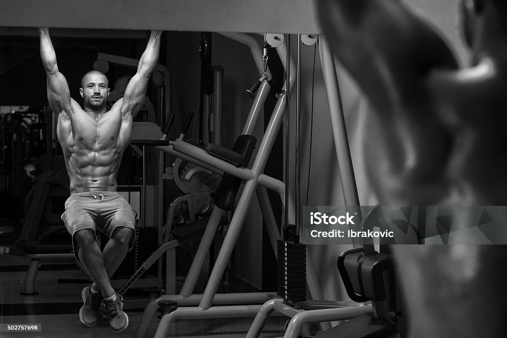 Young Man Performing Hanging Leg Raises Exercise Young Man Performing Hanging Leg Raises Exercise - One Of The Most Effective Ab Exercises 2015 Stock Photo