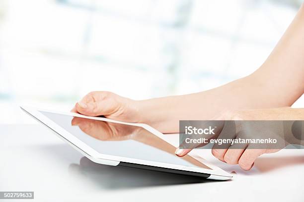 White Tablet With Blank Screen In The Hands On Table Stock Photo - Download Image Now