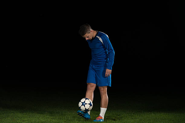 istock Professional Soccer Player Kicking Ball Isolated On Black 502760654
