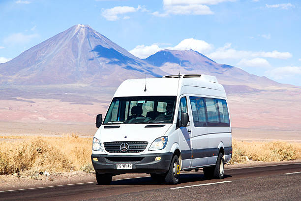 Mercedes-Benz Sprinter Antofagasta, Chile - November 15, 2015: White minibus Mercedes-Benz Sprinter drives at the intercity freeway at the background of a volcano. waterless stock pictures, royalty-free photos & images