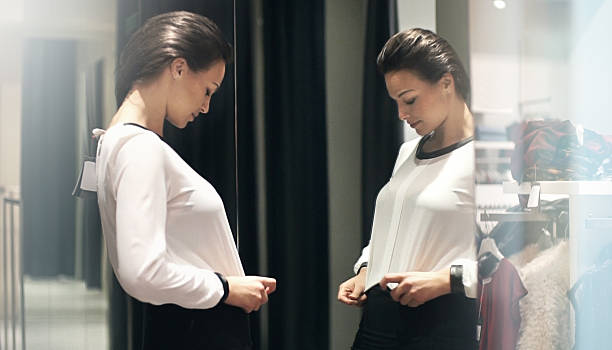Asian young woman in black clothes is looking at herself in the mirror in the living room