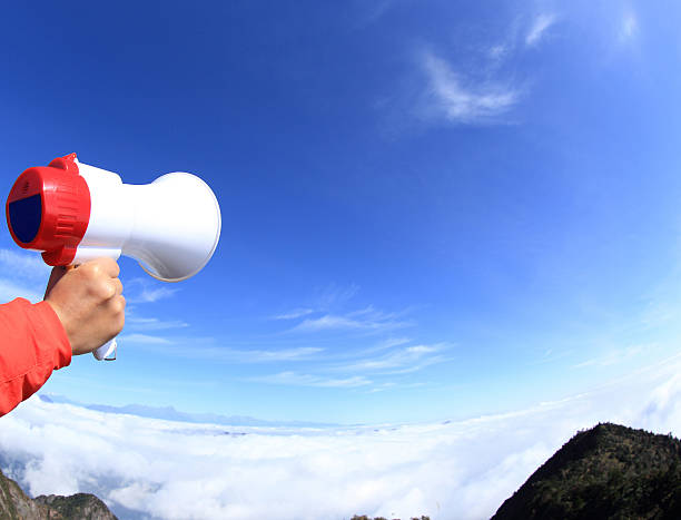 istock people hand hold loudspeaker to blue sky on mountain peak 502779292