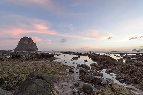 Photo of Sunset at rocky beach in Papuma, Indonesia.