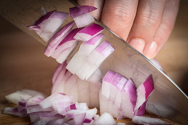 Chef choppig a red onion with a knife stock photo