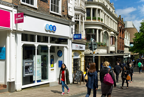 Norwich, England - May 13, 2014: People passing a TSB Bank branch in Guildhall Hill, Norwich, England. The British bank ‘TSB’ was formerly known as the Trustee Savings Bank and was incorporated into the Lloyds Banking Group in 2009. In the background is the famous Jarrolds store, on the corner of Exchange Street.