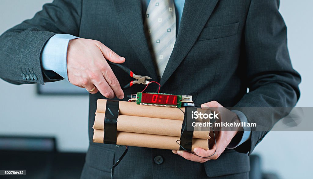 Man shows leadership and decision making while disarming bomb Concept of leadership under difficult circumstances: Businessman disarms a bomb with a wire cutter while it is counting down. Bomb Stock Photo
