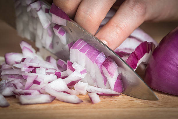 chef choppig cebola vermelha com uma faca. - spanish onion fotos imagens e fotografias de stock