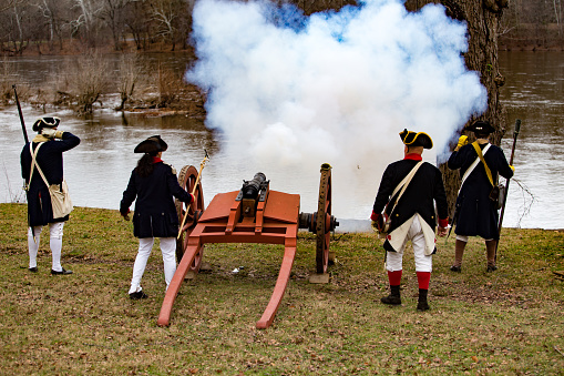 Washington Crossing, PA, USA - December 25, 2015: Reenactors fire a cannon when General Washington and the Continental Army reached New Jersey after crossing the Delaware River in boats on Christmas Day.