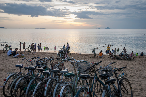 Nha Trang, Vietnam - July 8, 2007: A line of bicycles, ridden by people who had come to swim, is parked at the beach at sunrise in Nha Trang, Vietnam.