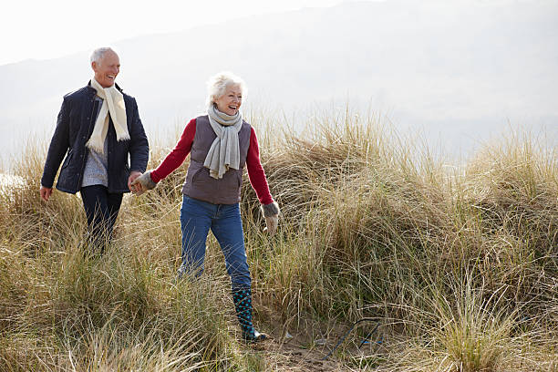 istock Senior Couple Walking Through Sand Dunes On Winter Beach 502814887