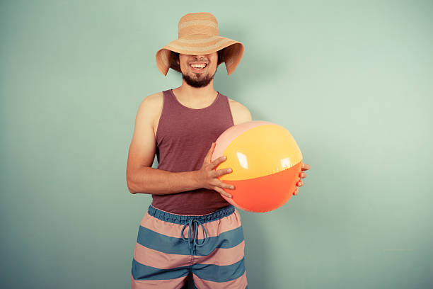 istock Happy young man with beach ball and sun hat 502820179