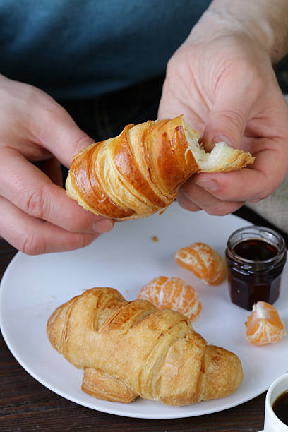 istock man eating a croissant with jam for breakfast 502821790