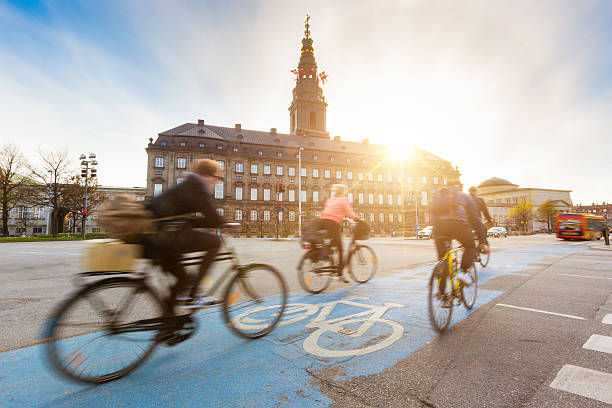 People going by bike in Copenhagen Blurred people going by bike in Copenhagen, with Christiansborg palace on background. Many persons prefer biking instead of taking car or bus to move around the city. Urban lifestyle concept. danish culture photos stock pictures, royalty-free photos & images