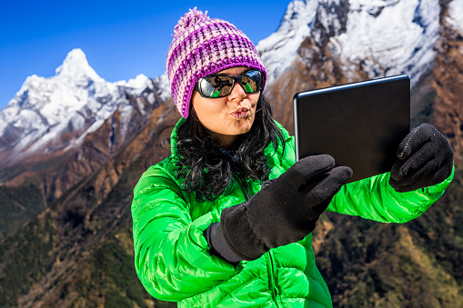 Happy young woman taking selfie in Himalayas. She is wearing green jacket and holding a digital tablet. Mount Ama Dablam on the background. Mount Everest National Park. This is the highest national park in the world, with the entire park located above 3,000 m ( 9,700 ft). This park includes three peaks higher than 8,000 m, including Mt Everest. Therefore, most of the park area is very rugged and steep, with its terrain cut by deep rivers and glaciers. Unlike other parks in the plain areas, this park can be divided into four climate zones because of the rising altitude. The climatic zones include a forested lower zone, a zone of alpine scrub, the upper alpine zone which includes upper limit of vegetation growth, and the Arctic zone where no plants can grow. The types of plants and animals that are found in the park depend on the altitude.http://bem.2be.pl/IS/nepal_380.jpg