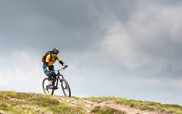 Thundery mountainbiking in the Carinthian Mountains, Austria A male mountainbiker is riding downhill above the treeline in the Carinthian Mountains on a thundery summer day. elbow pad stock pictures, royalty-free photos & images