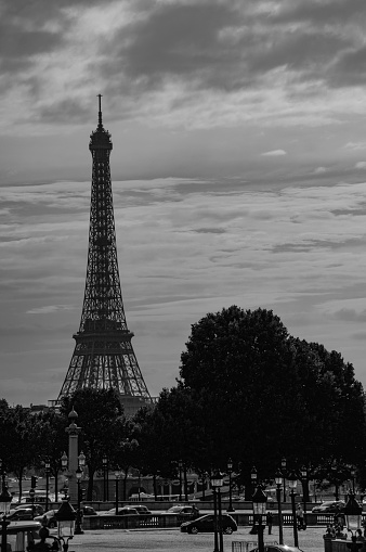 A dramatic black and white picture of the Eiffel Tower viewed from the Seine.