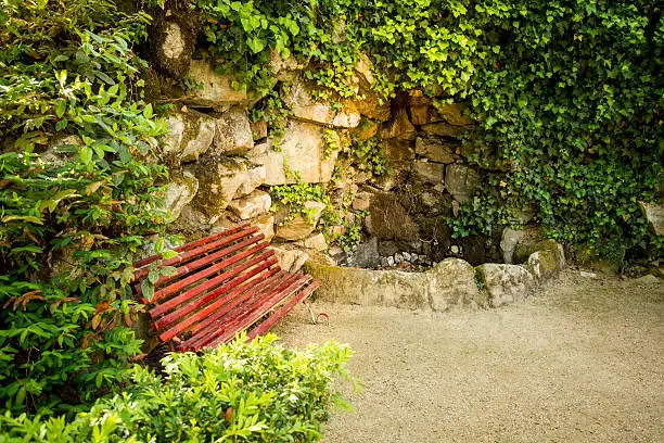 Red bench in the park surrounded by bindweeds in the Public Garden City "Pedras Salgadas" in Tras-os-Montes. Portugal.