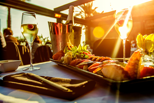 Luxury restaurant table with sushi dish , champagne and the sunset on Barcelona beach 