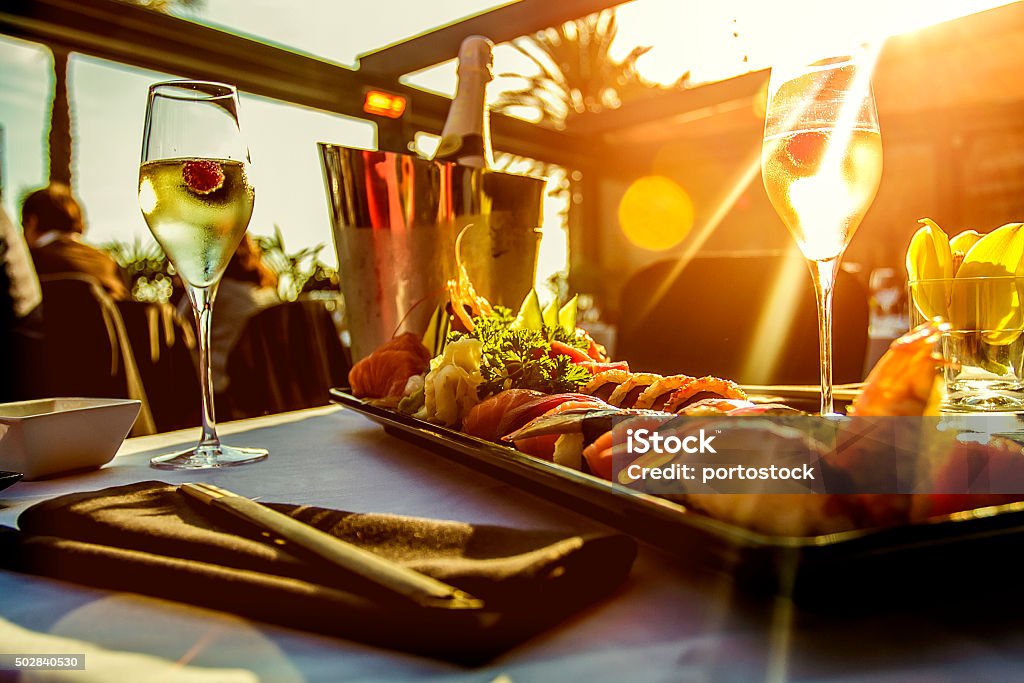 Luxury restaurant table on sunset Luxury restaurant table with sushi dish , champagne and the sunset on Barcelona beach  Restaurant Stock Photo