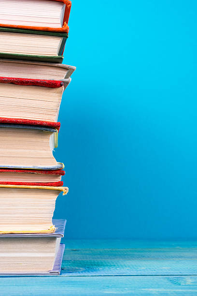 istock Stack of colorful hardback books, open book on blue background 502842018