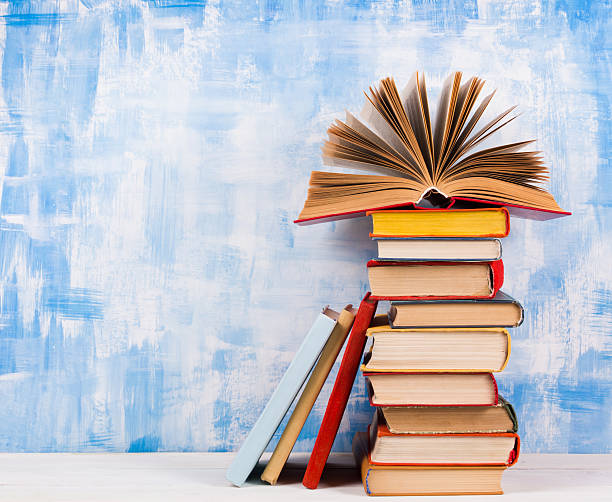 istock Stack of colorful hardback books, open book on blue background 502842350
