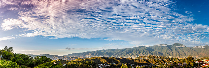 Panoramic image of eastern Caracas city aerial view at late afternoon. Venezuela.  Showing El Avila mountain also known as El Avila National Park (Guaraira Repano).  Santiago de Leon de Caracas, is the capital city of Venezuela and center of the Greater Caracas Area. It is located in the northern part of the country, following the contours of the narrow Caracas Valley and the \