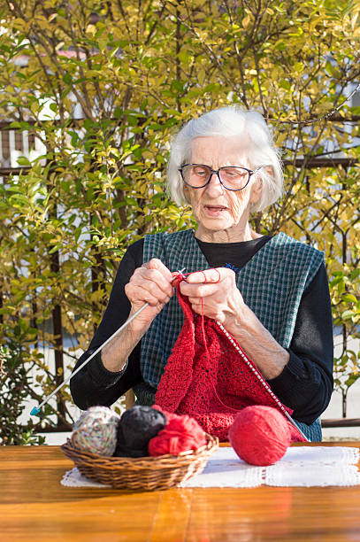 istock 90 years old woman knitting a red sweater 502843020