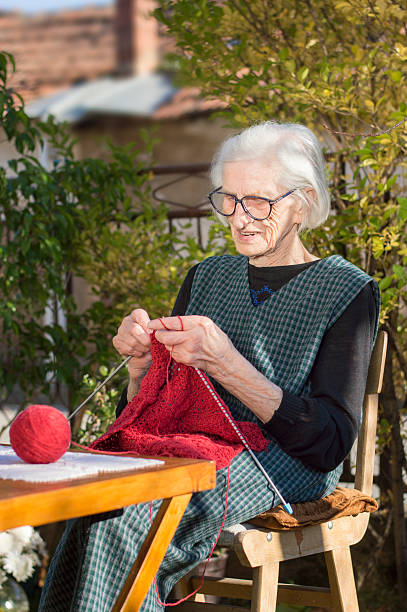 istock 90 years old woman knitting a red sweater 502843144