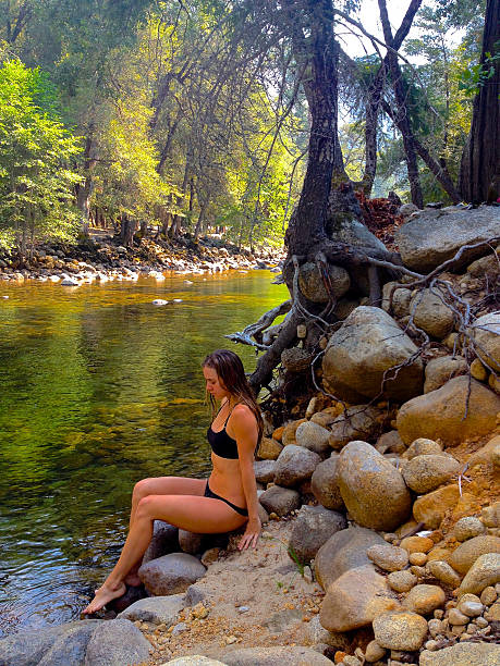 Pretty girl sitting next to a rocky river stock photo