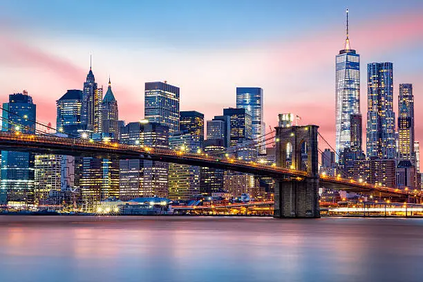 Brooklyn Bridge at and the Lower Manhattan skyline under a purple sunset