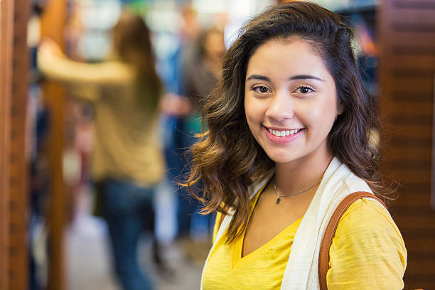 Pretty high school or college student stands in school library