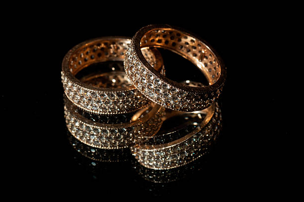 Wedding rings lie on a mirror, black background
