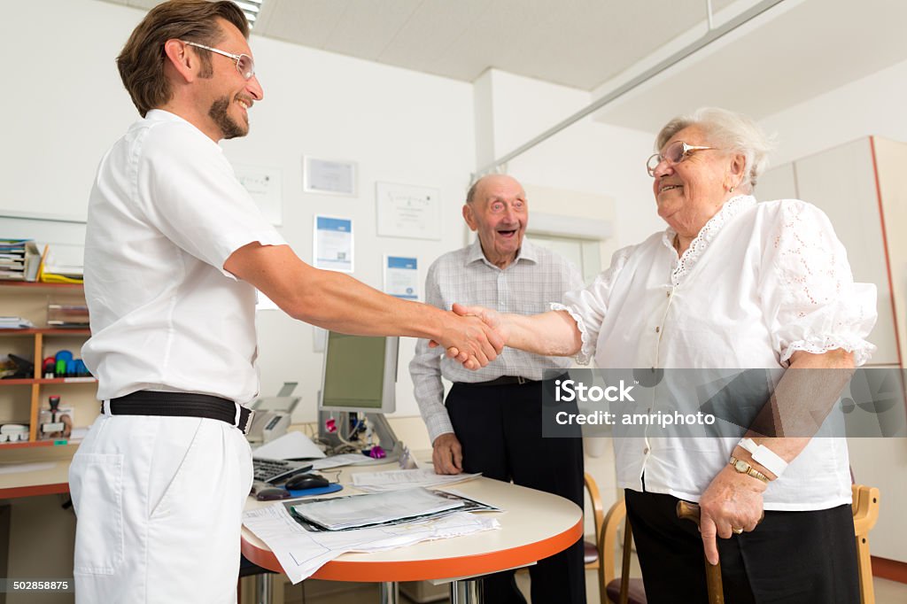 relieved elderly couple saying goodbye happy senior couple shaking hands with friendly doctor 80-89 Years Stock Photo