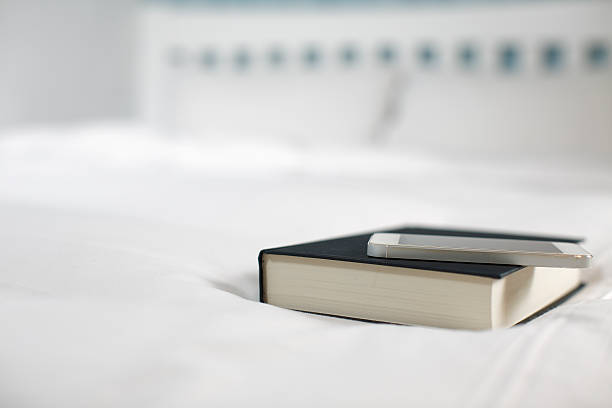 istock smartphone and book on the bed 502867934